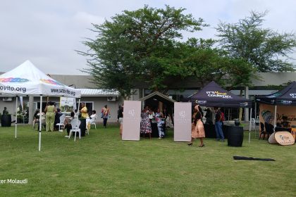 Outdoor event with tents and people gathering.