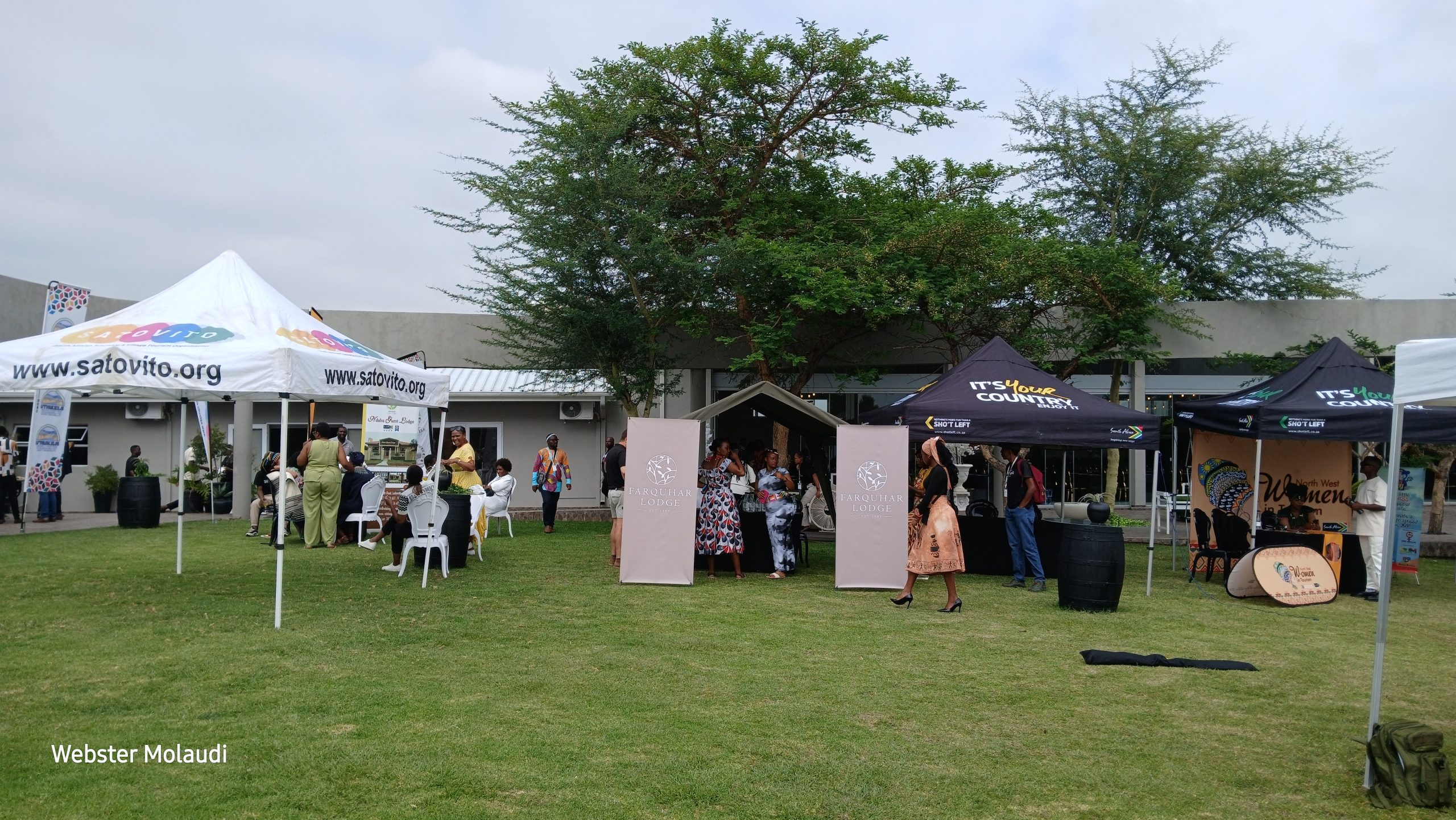 Outdoor event with tents and people gathering.