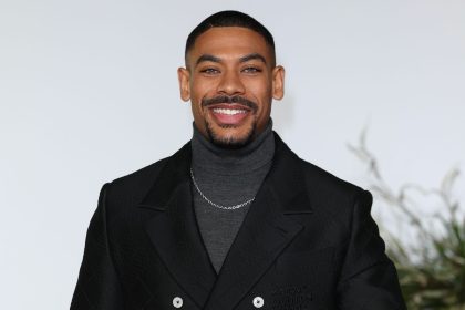 Smiling man in black jacket, grey turtleneck