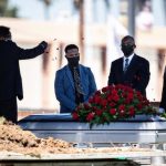 Funeral ceremony with mourners by a casket.
