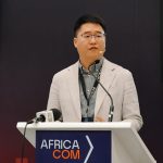 Speaker at Africa Com conference podium.