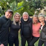 Smiling people posing outdoors together in garden.