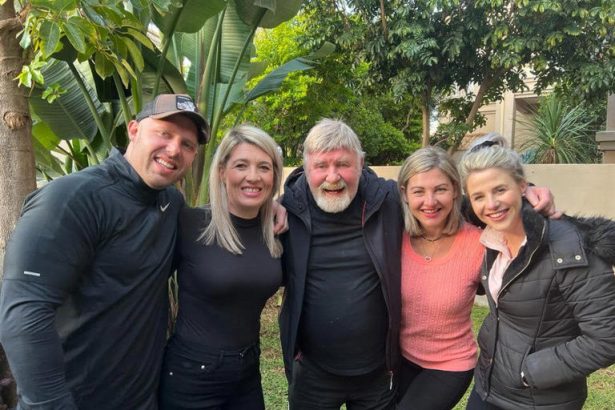 Smiling people posing outdoors together in garden.