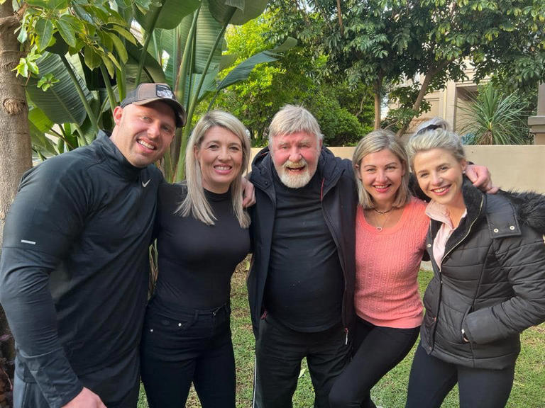 Smiling people posing outdoors together in garden.