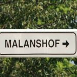 Sign pointing to Malanshof amid trees.