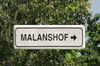 Sign pointing to Malanshof amid trees.
