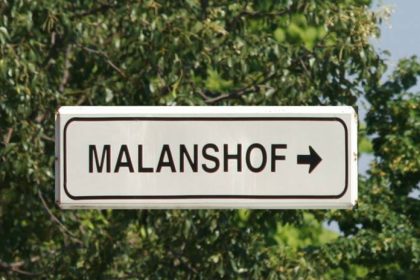 Sign pointing to Malanshof amid trees.