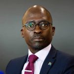 Person in suit with South African flag pin.