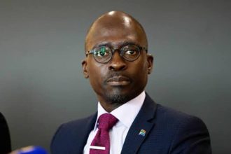 Person in suit with South African flag pin.