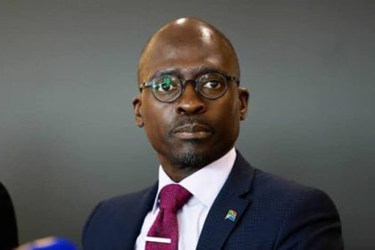 Person in suit with South African flag pin.
