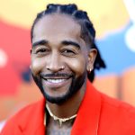 Smiling person in red suit and colourful background.