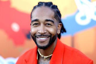 Smiling person in red suit and colourful background.