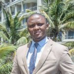 Man in suit, standing by palm trees and building