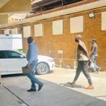 People walking in a parking area near cars.