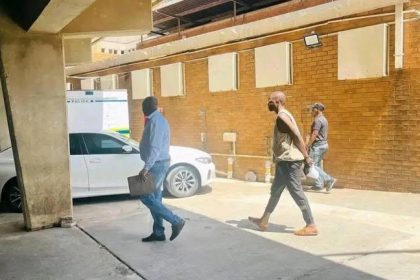 People walking in a parking area near cars.