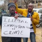 Protesters holding 'Illegal Immigration is Crime' sign.