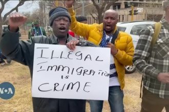 Protesters holding 'Illegal Immigration is Crime' sign.