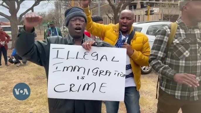 Protesters holding 'Illegal Immigration is Crime' sign.