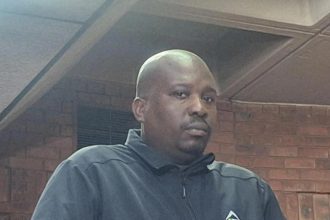 Man in black jacket inside brick building