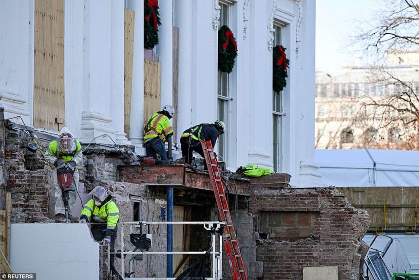 Construction workers repair building facade with seasonal decor.