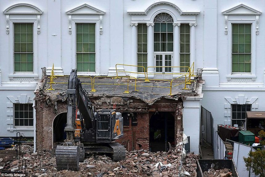 Excavator demolishing building facade with safety railings.