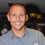 Smiling person in checkered shirt at event.