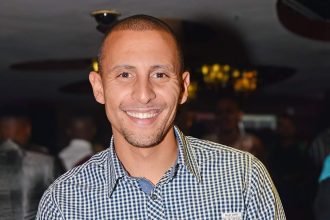 Smiling person in checkered shirt at event.