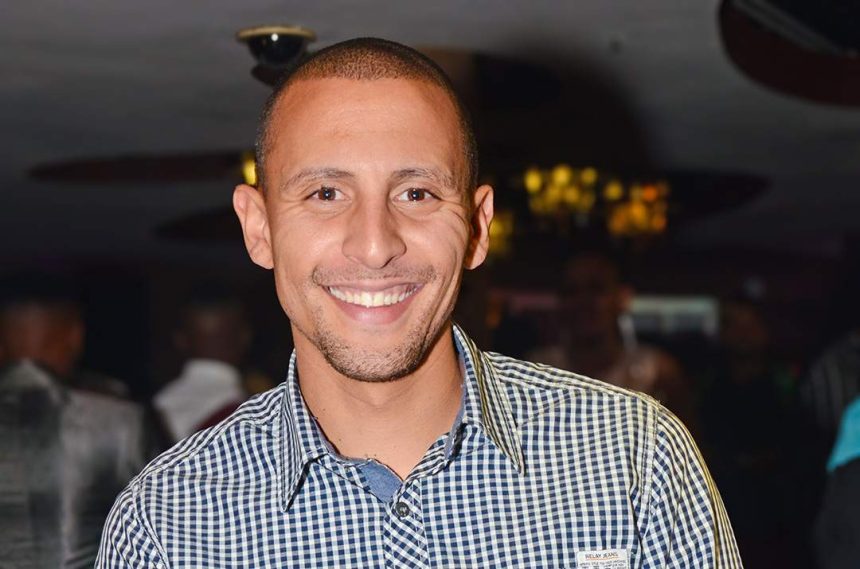 Smiling person in checkered shirt at event.