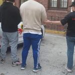 Hawks officers arrest suspects near an official vehicle.