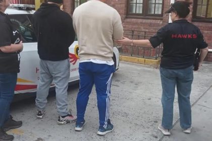 Hawks officers arrest suspects near an official vehicle.