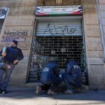 Police inspect closed graffiti-covered storefront