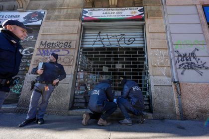 Police inspect closed graffiti-covered storefront
