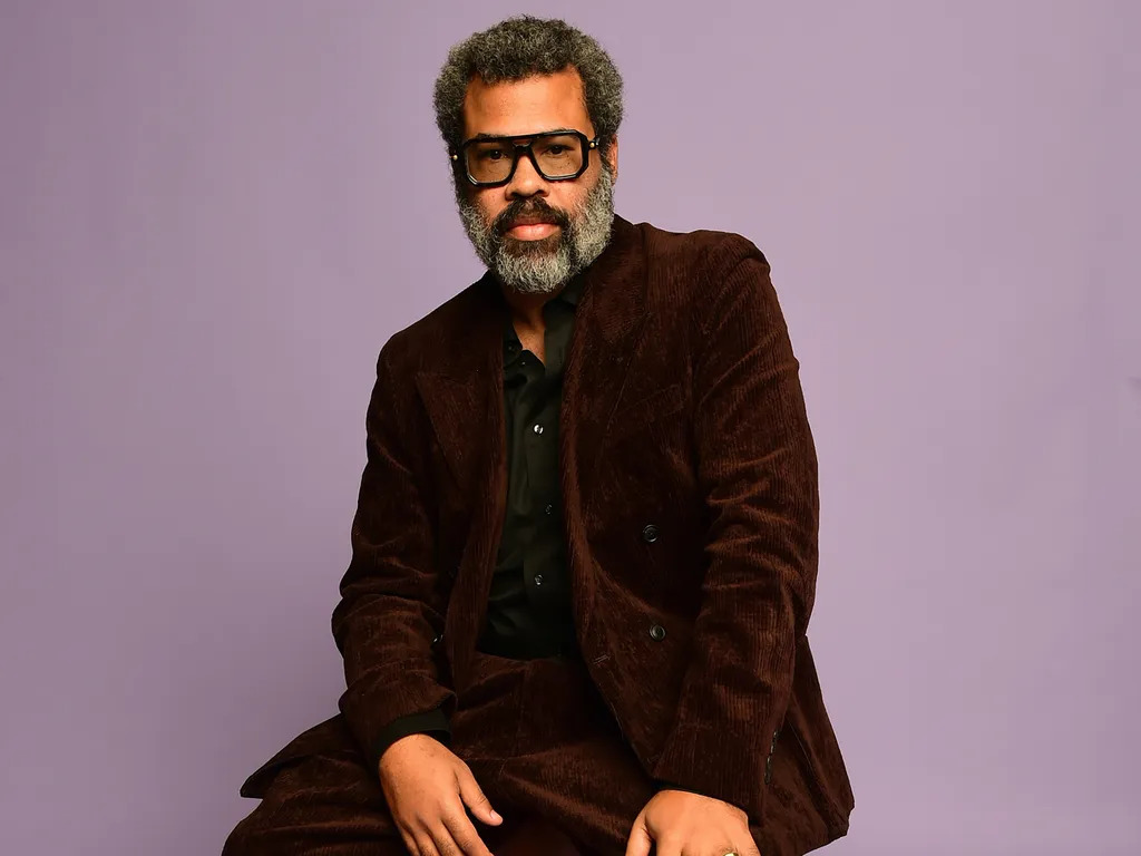 Man in brown suit posing against purple background