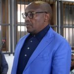 Man in blue suit standing in courtroom.