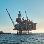 Offshore oil rig platform with supply vessel nearby.