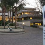 PetroSA headquarters entrance with signage and palm trees.