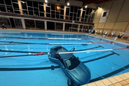 Car submerged in swimming pool at night.