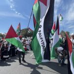 People marching with large Palestinian flags outdoors
