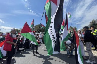 People marching with large Palestinian flags outdoors
