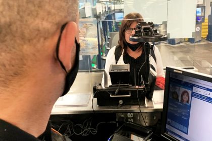 US border control officers processing travelers at an international airport using biometric screening technology