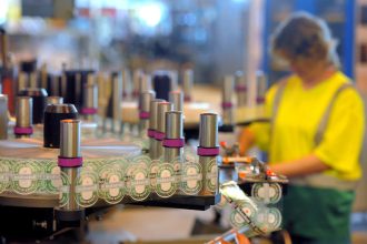 A worker checks labelling of bottles of beer at the production line of Dutch brewer Heineken factory on June 7, 2011 in Schiltigheim, eastern France, during an official visit announcing the group's goals for sustainable development, by reducing the amount of glass in some beer bottles' production, and lowering by 20 percent the energy needed at its Alsacian factory. [Photo by PATRICK HERTZOG/AFP via Getty Images]
