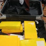 Suitcase filled with yellow wrapped packages
