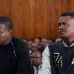 Two men seated in courtroom during hearing