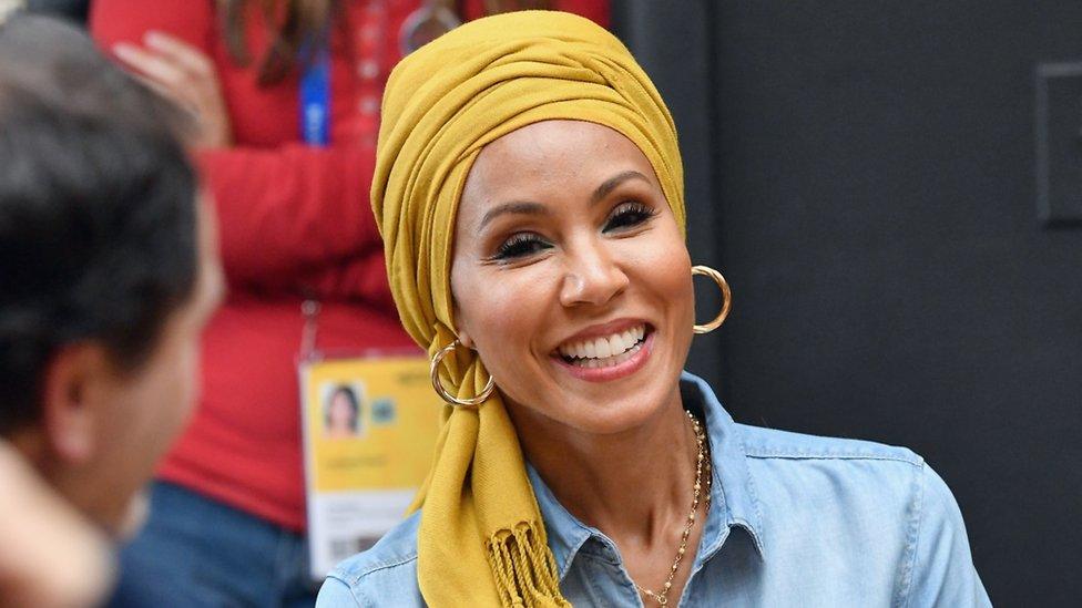Smiling woman wearing yellow headscarf and hoop earrings