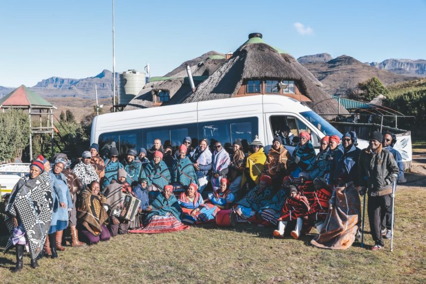 Group in traditional blankets before mountain lodge