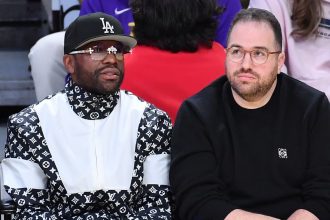 Two men seated courtside at basketball game
