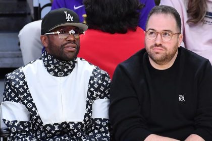 Two men seated courtside at basketball game