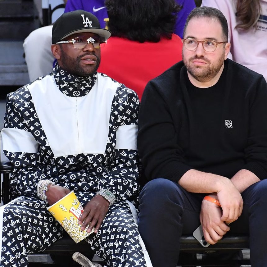 Two men seated courtside at basketball game
