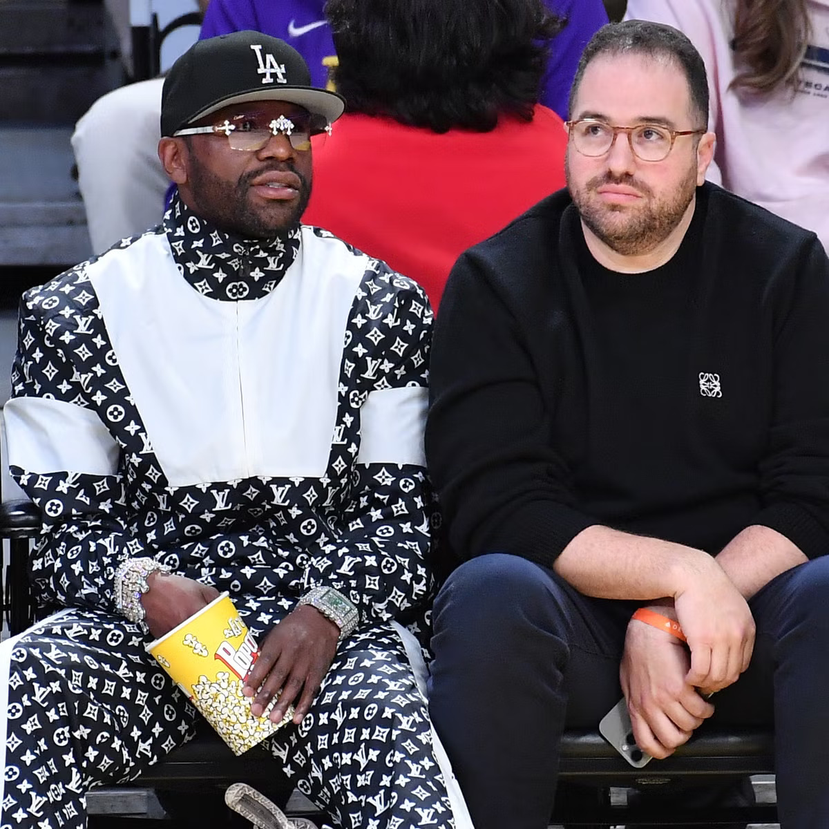 Two men seated courtside at basketball game
