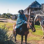 Two people riding horses in rural village
